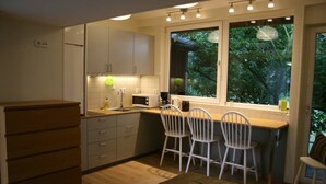 Una cocina compacta con ventana, armarios blancos y un aparador de madera.
