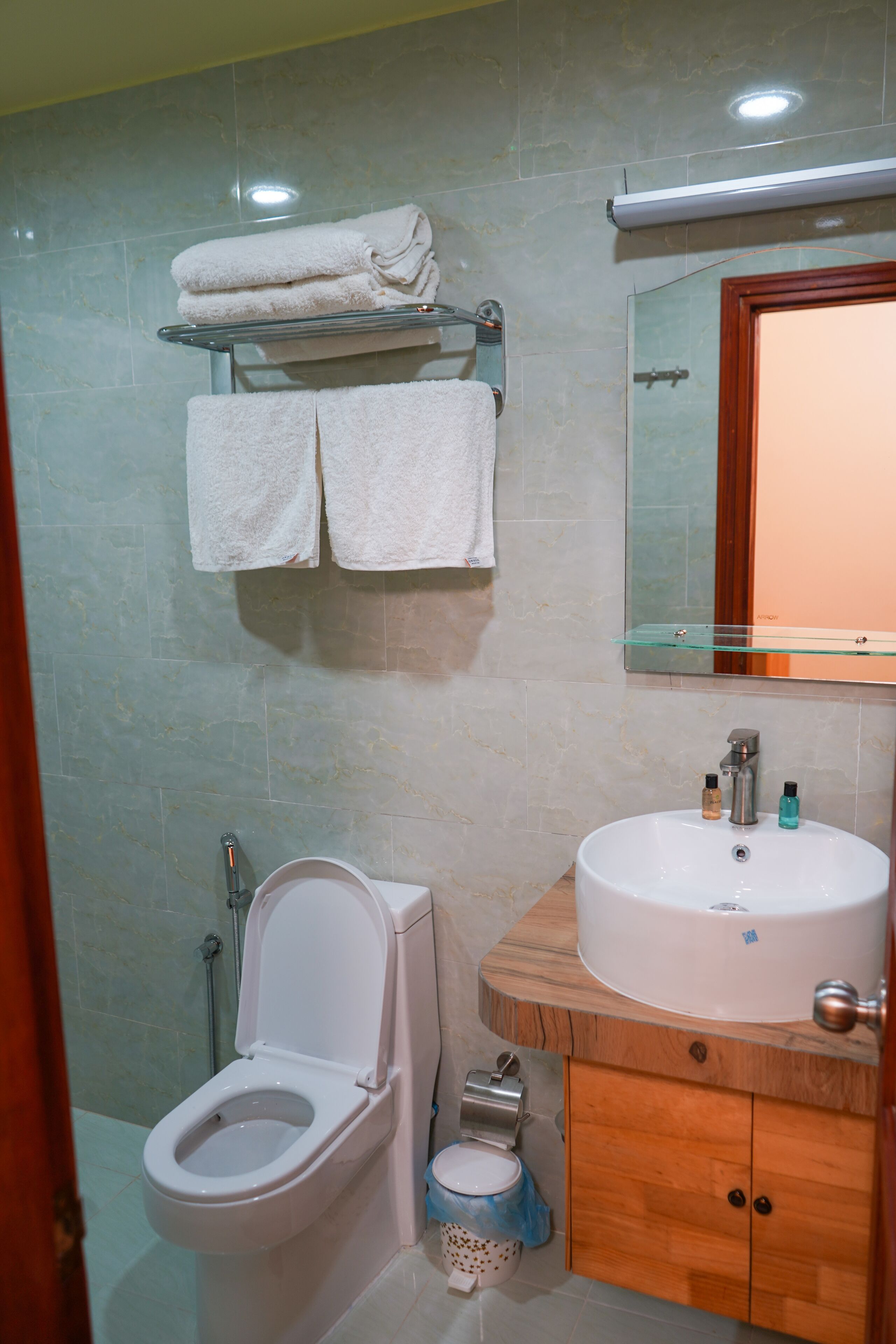 Un baño con inodoro, lavamanos y perchero para toallas.