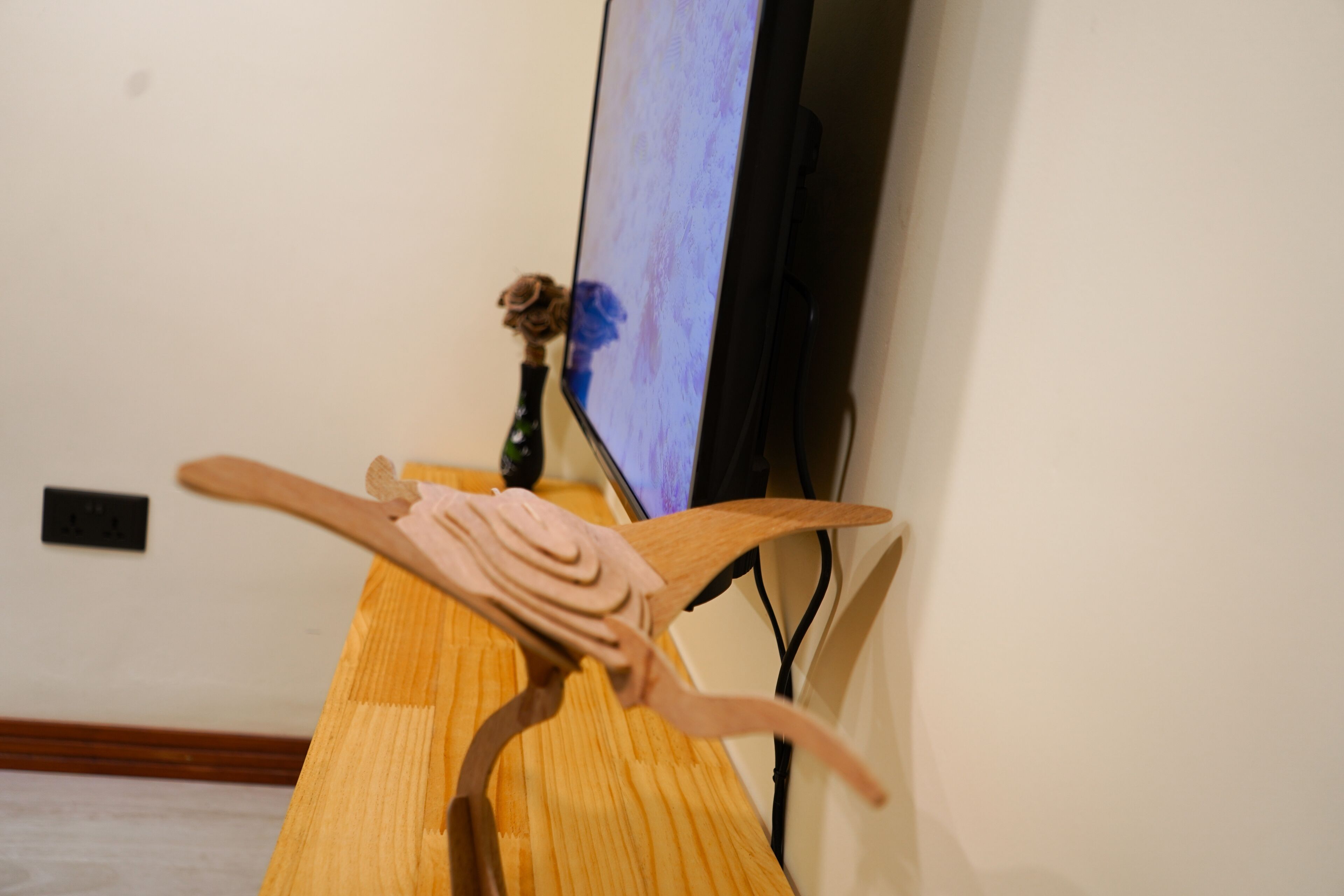 A wooden sculpture with a bird-like figure on a wooden stand.