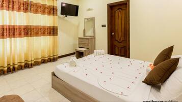 A hotel room with a bed, a TV, a wooden door, and a mirror.