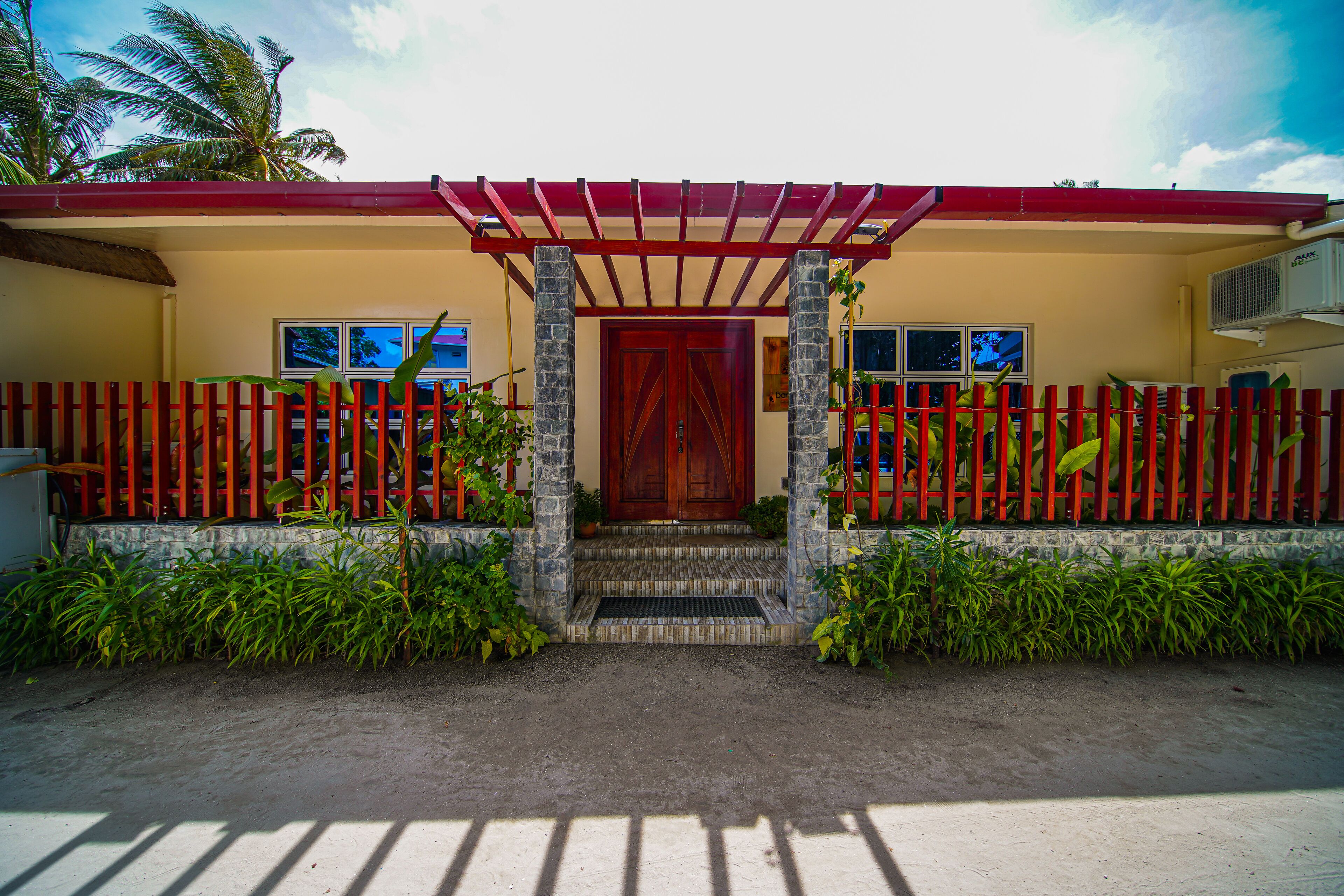 Una casa con techo rojo, puerta de madera y cerca roja.