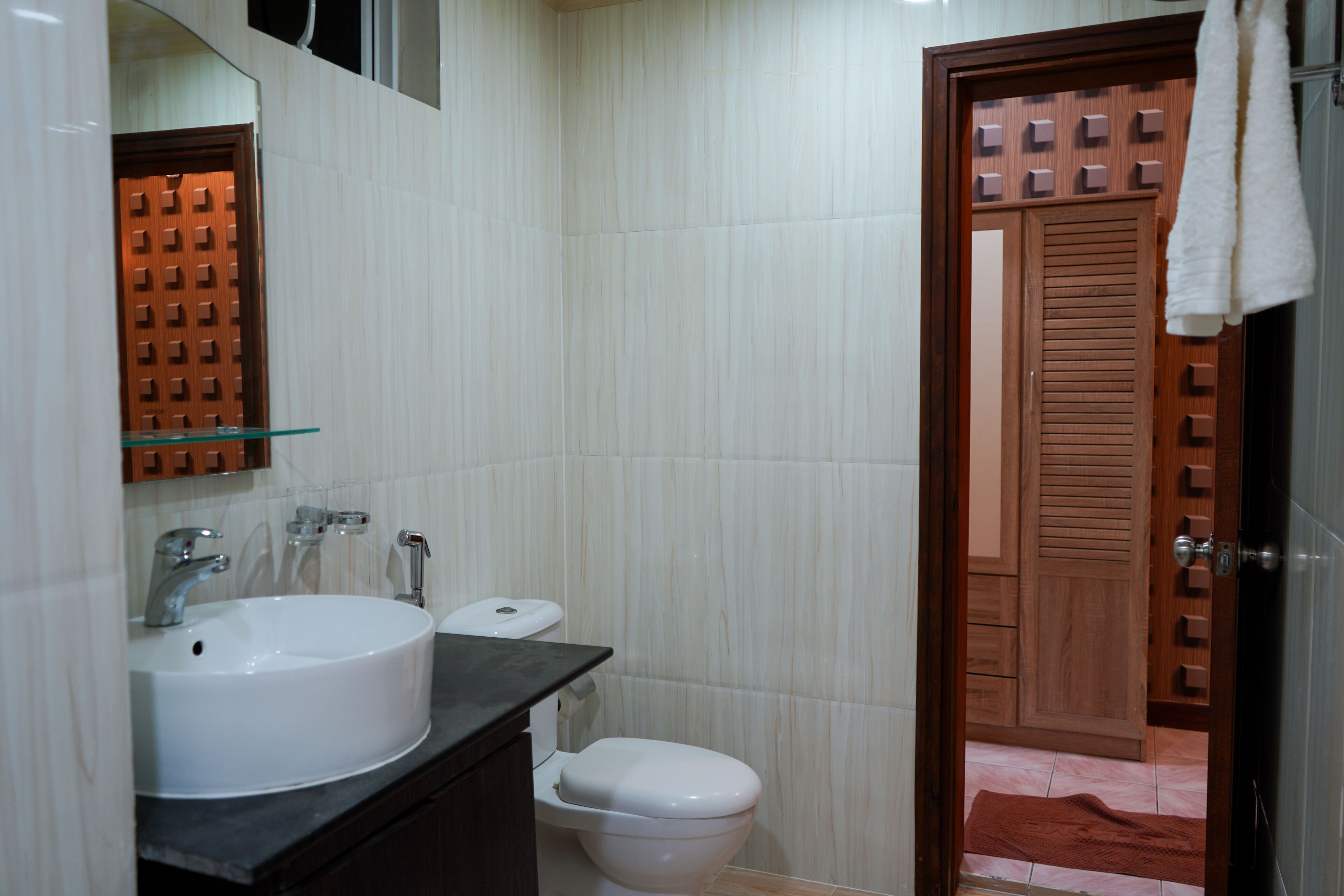 Casa de banho com lavatório branco, sanita e porta de madeira.