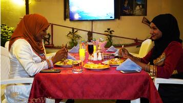 Two women dining at a table with a red tablecloth, surrounded by various dishes and drinks.