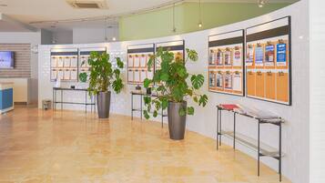 A reception area with a tiled floor, potted plants, bulletin boards with printed materials, and a television on the wall.