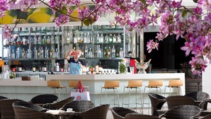 A bar area with wicker chairs, a bar counter, and shelves stocked with bottles. - Barut B Suites - All Inclusive (Manavgat)