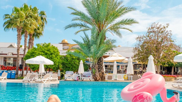 A pool area with lounge chairs, a flamingo float, and a cocktail with a slice of fruit. - Barut B Suites - All Inclusive (Manavgat)