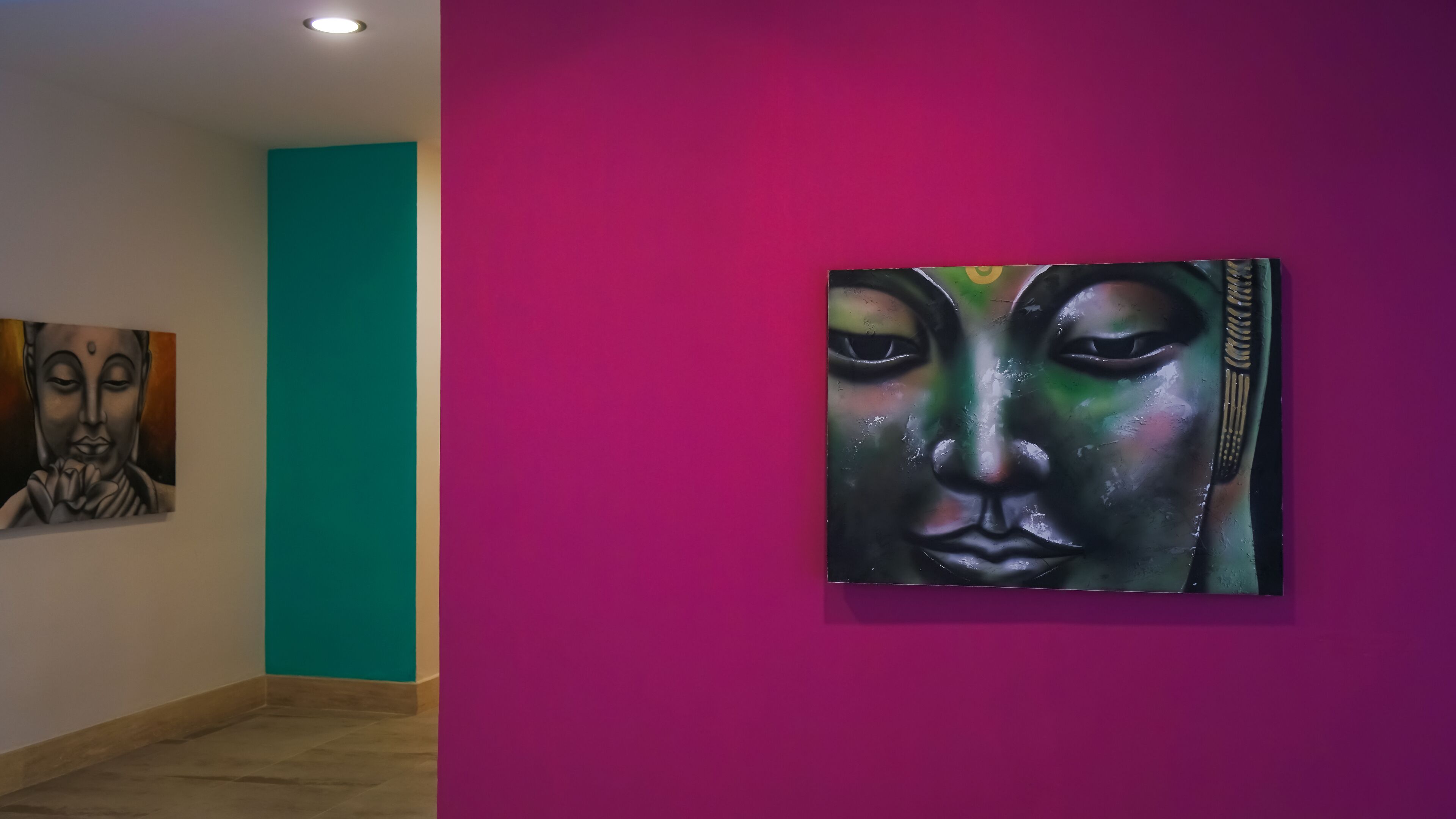 An art gallery with a teal wall and a purple wall displaying paintings.