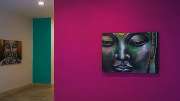 An art gallery with a teal wall and a purple wall displaying paintings.