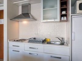 A kitchen with white cabinets, a stainless steel sink, and a range hood.