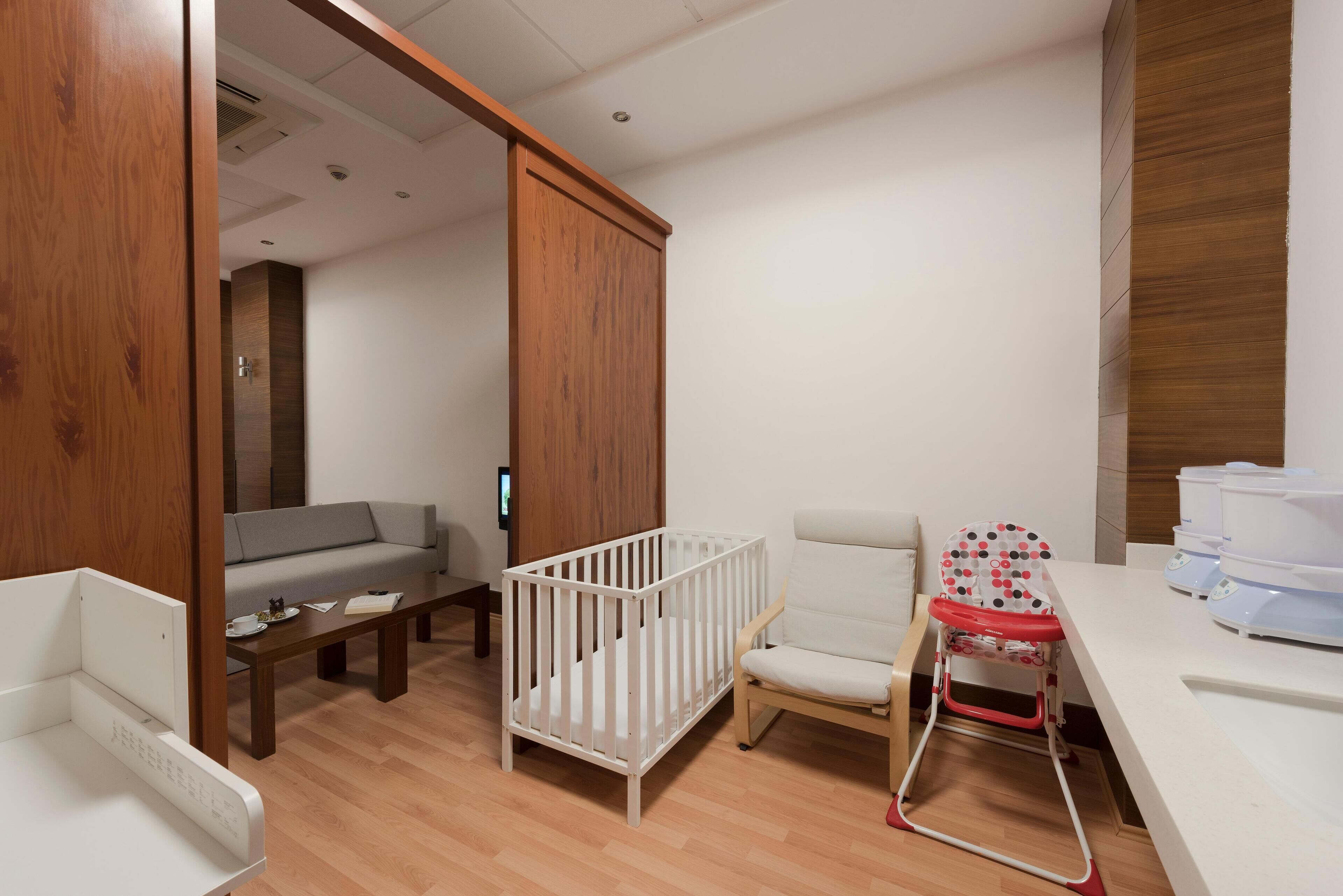 A baby room with a crib, high chair, and a sofa.
