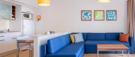 A modern living room with a blue sectional sofa, a wooden coffee table, and two pendant lights.