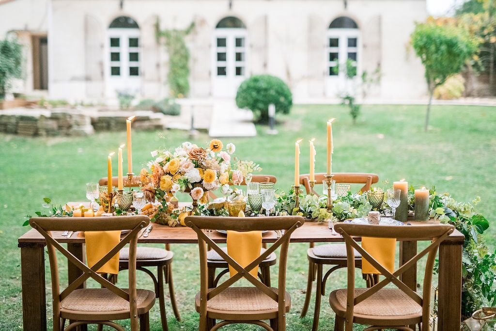 Un espace de restauration en plein air avec une table dressée pour six personnes, entourée de chaises dotées de coussins jaunes.