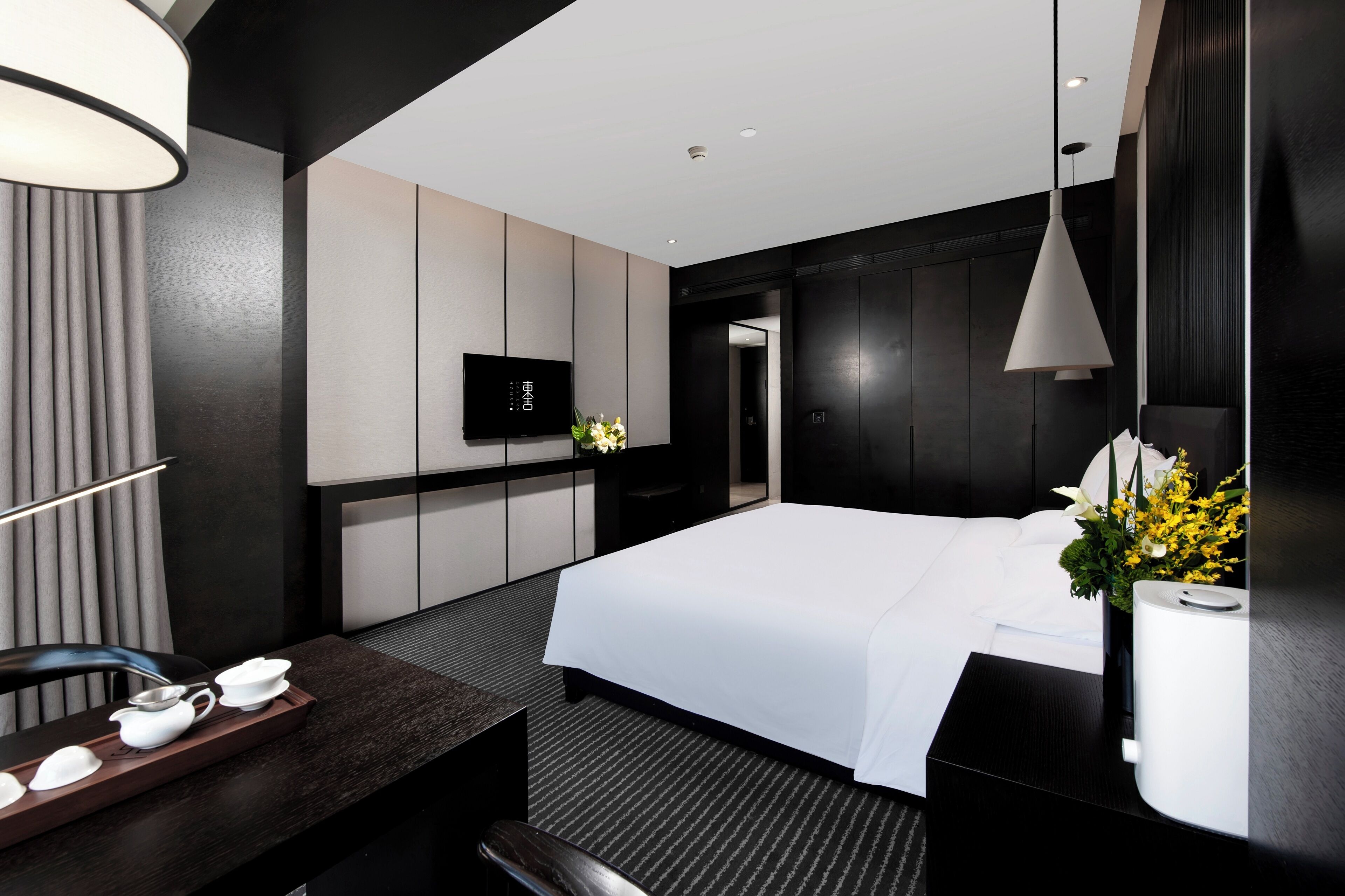 Une chambre d’hôtel moderne dotée d’un grand lit, d’un téléviseur à écran plat, d’un bureau avec un service à thé et d’un grand miroir.