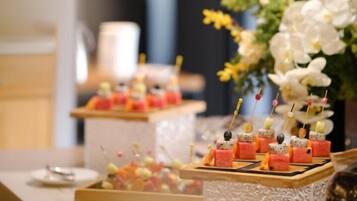 A dessert display with various treats on skewers, a floral arrangement, and a table setting with plates and cutlery.