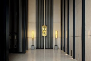 A modern building entrance with vertical lines and a central illuminated sign.