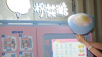 A person holding a cotton candy with a digital screen displaying a 'DIY' section in the background.