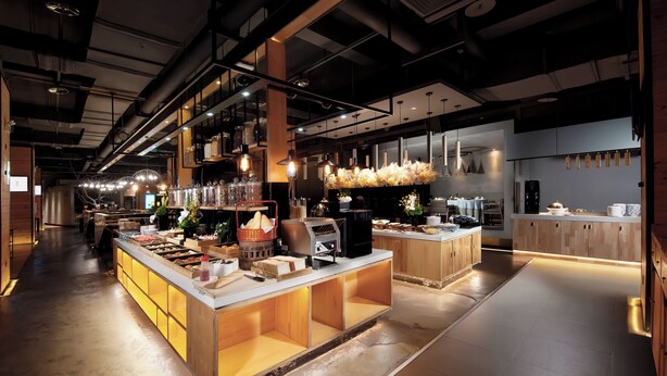 Una cocina moderna con armarios de madera, una isla central con horno integrado e iluminación colgante.