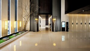 Un vestíbulo de hotel moderno con piso pulido, altas columnas y una recepción.