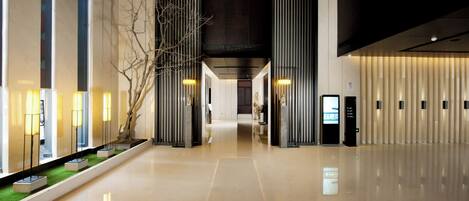 A modern hotel lobby with a polished floor, tall columns, and a reception desk.