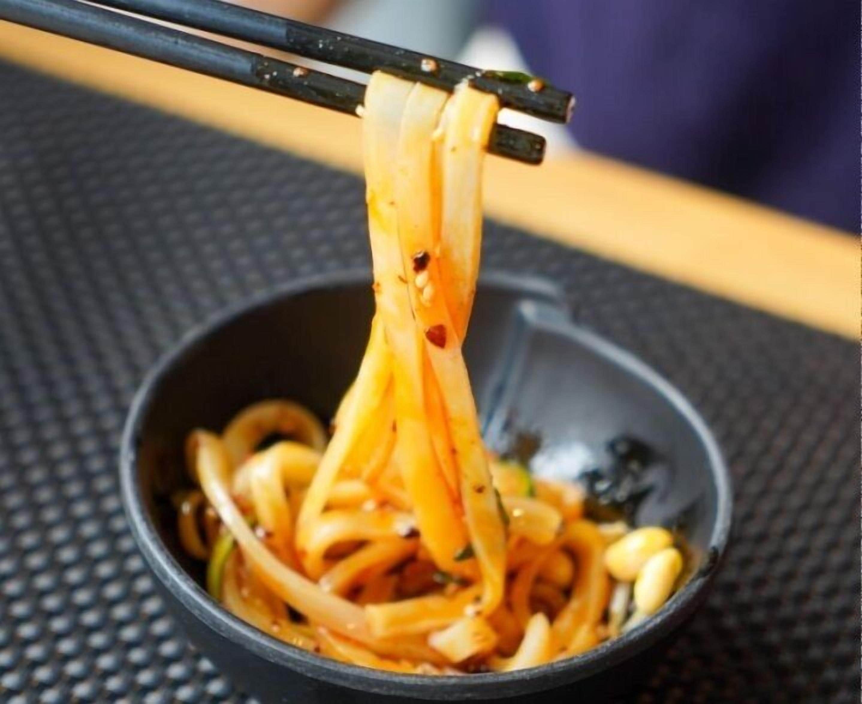 Un cuenco de fideos que se levanta con palillos.