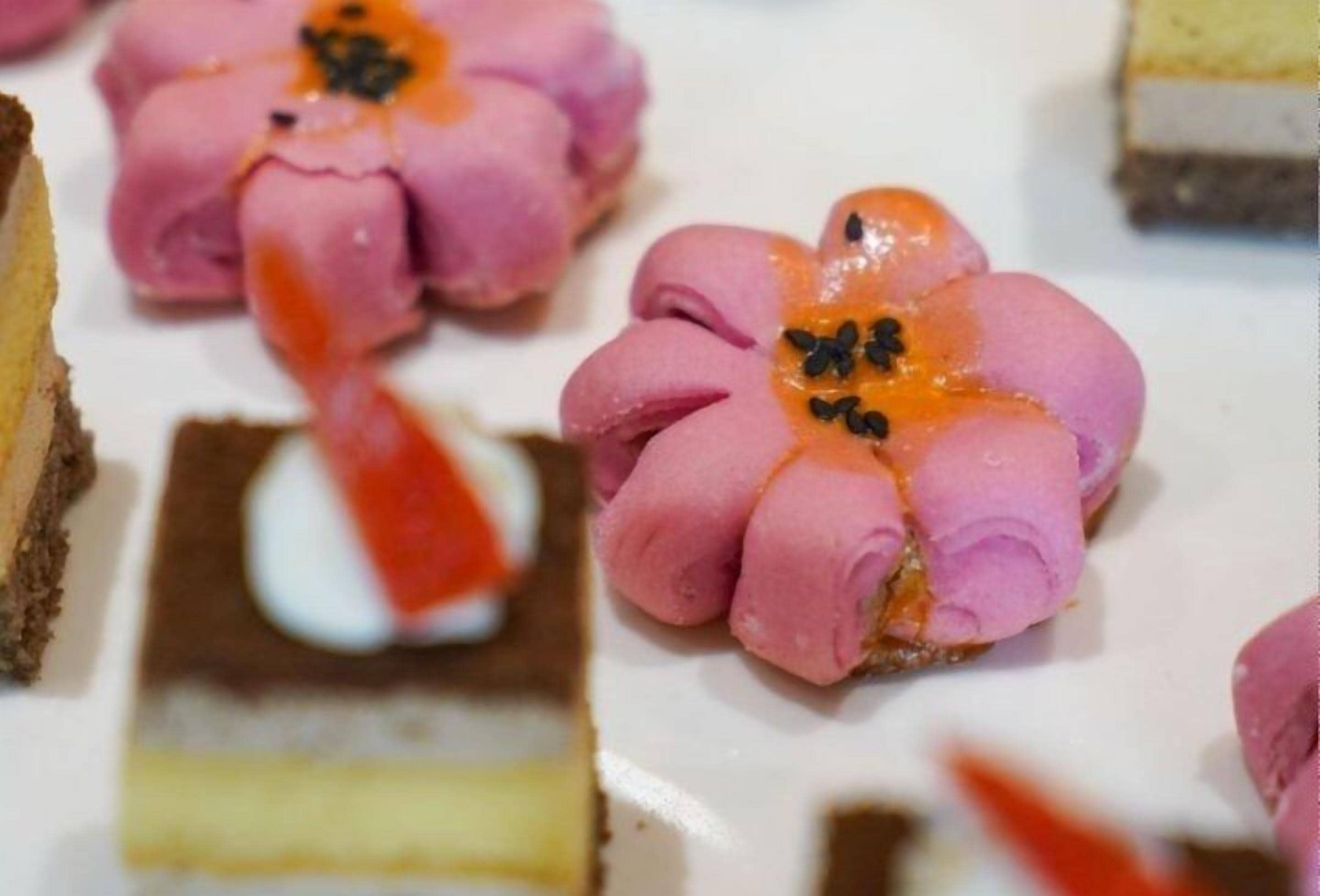 A dessert with pink icing flowers and a white cream center.