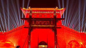 Una puerta tradicional china con elaboradas esculturas y fachada iluminada en rojo.