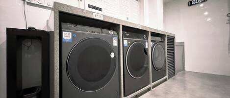 A row of front-loading washing machines in a commercial setting.