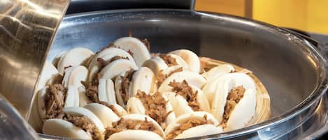 Un bufé con bollos de pan blanco cubiertos de carne desmenuzada.