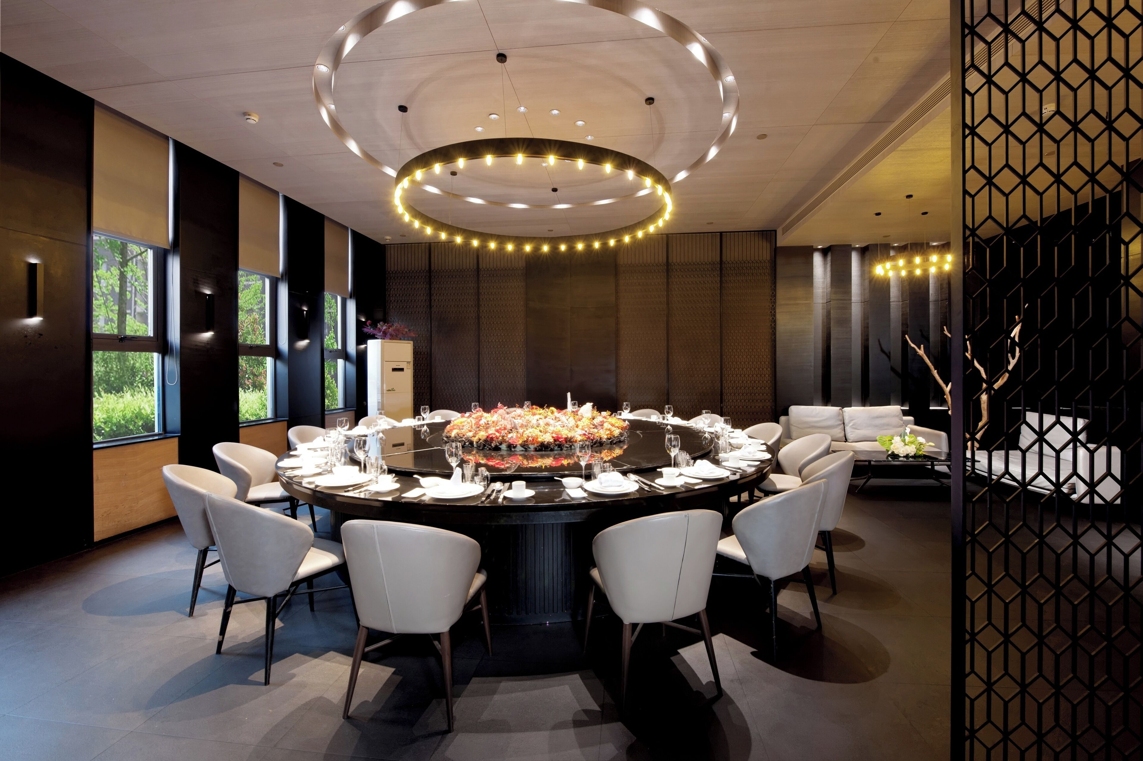 Un espace repas moderne avec une table ronde pour six personnes, entourée de chaises blanches.