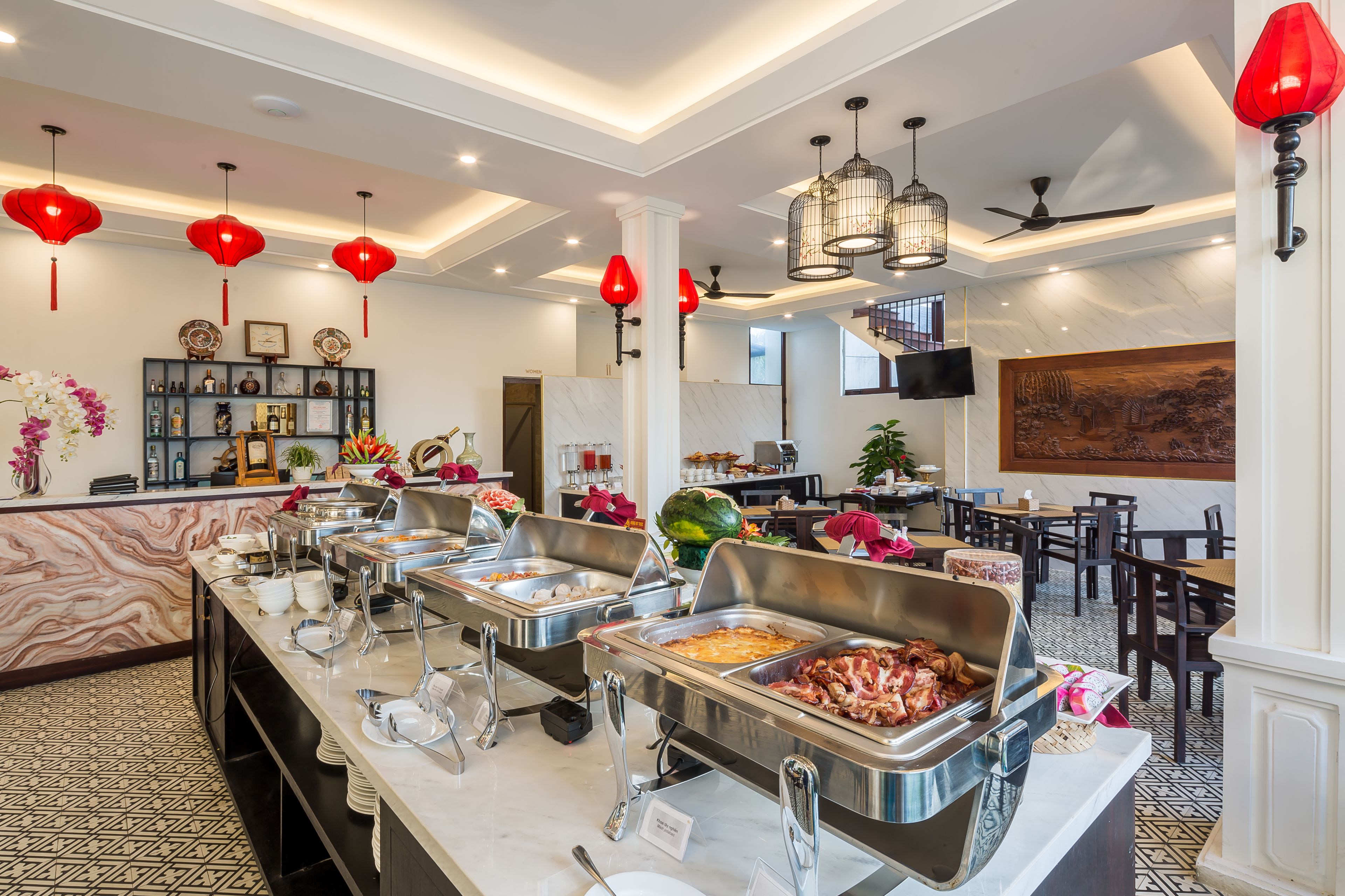 A buffet area with multiple food stations, a seating area with tables and chairs, and a decorative wall with artwork.