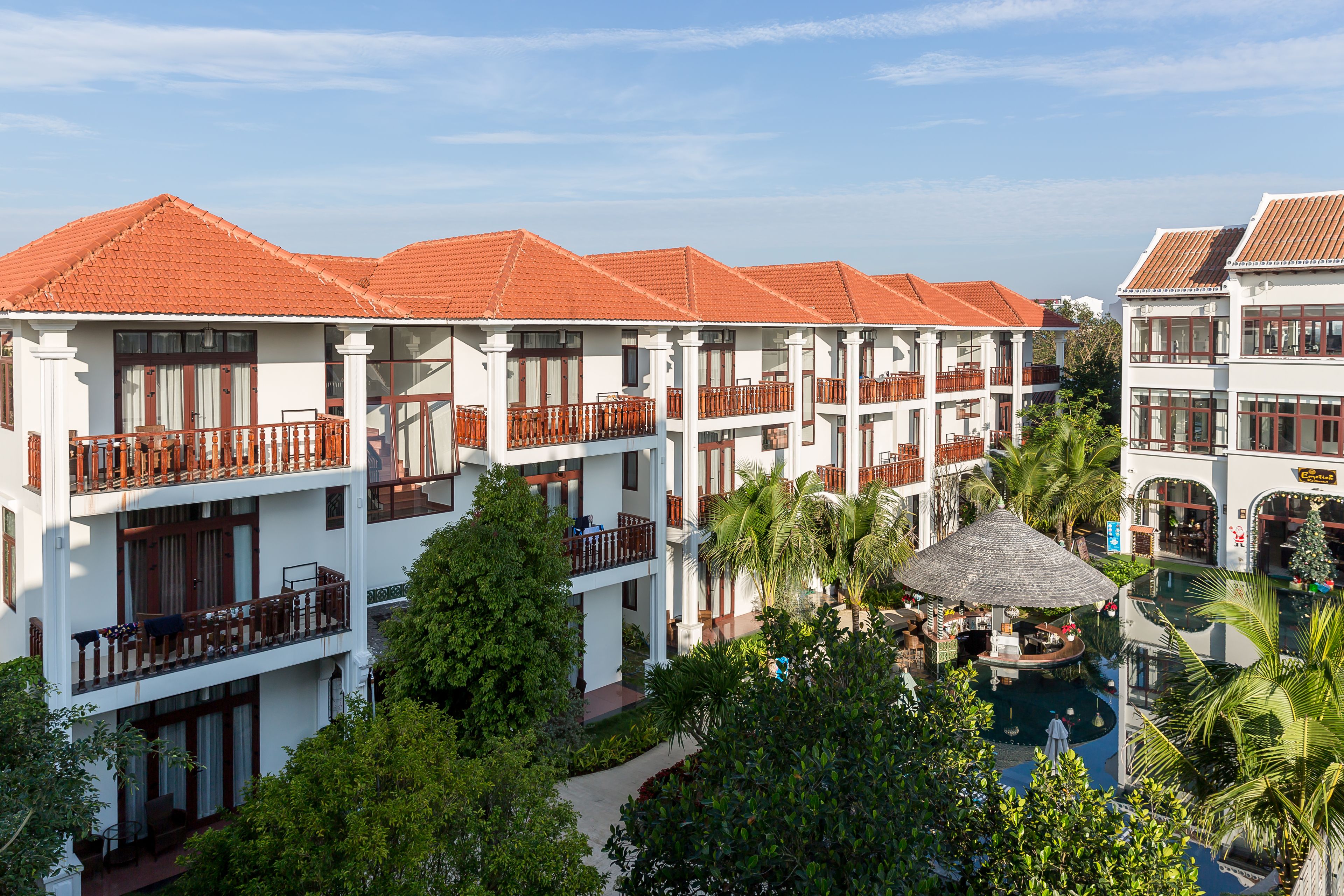 Un hôtel doté de nombreux balcons, d’une piscine et d’une végétation luxuriante.