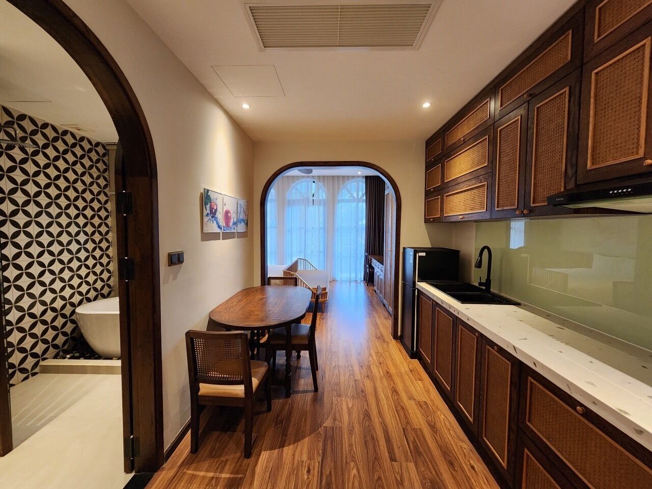 A modern kitchen with wooden cabinets, a dining table, and a view to the outside.