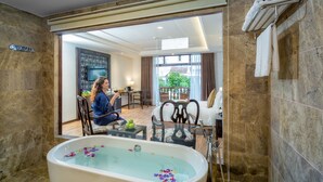 A modern bathroom with a large bathtub, a glass-enclosed shower area, and a view of a balcony with outdoor furniture. - Hoi An Emotion Boutique Villa (Da Nang)