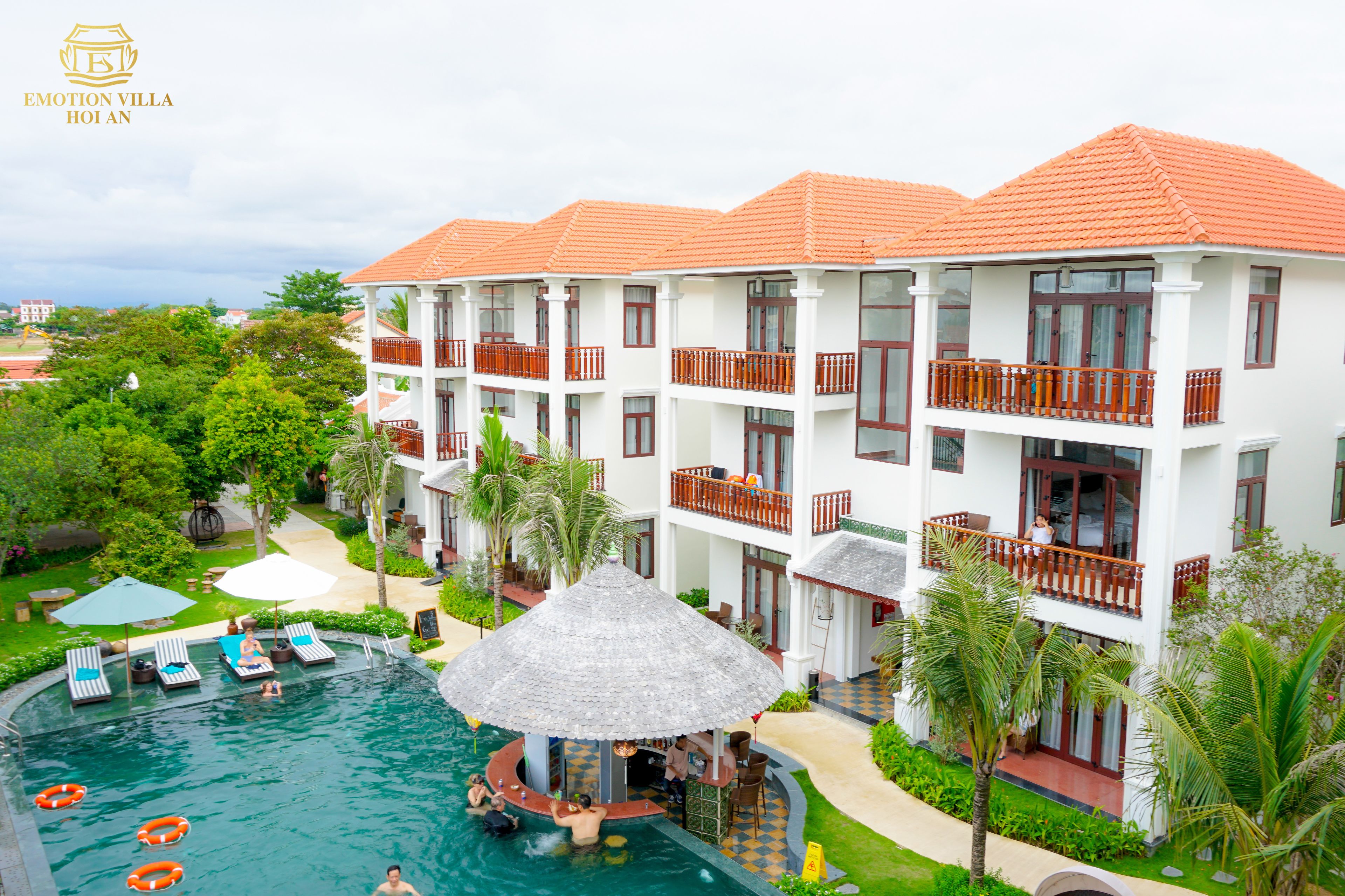 A hotel with multiple balconies, a swimming pool, and lush greenery.