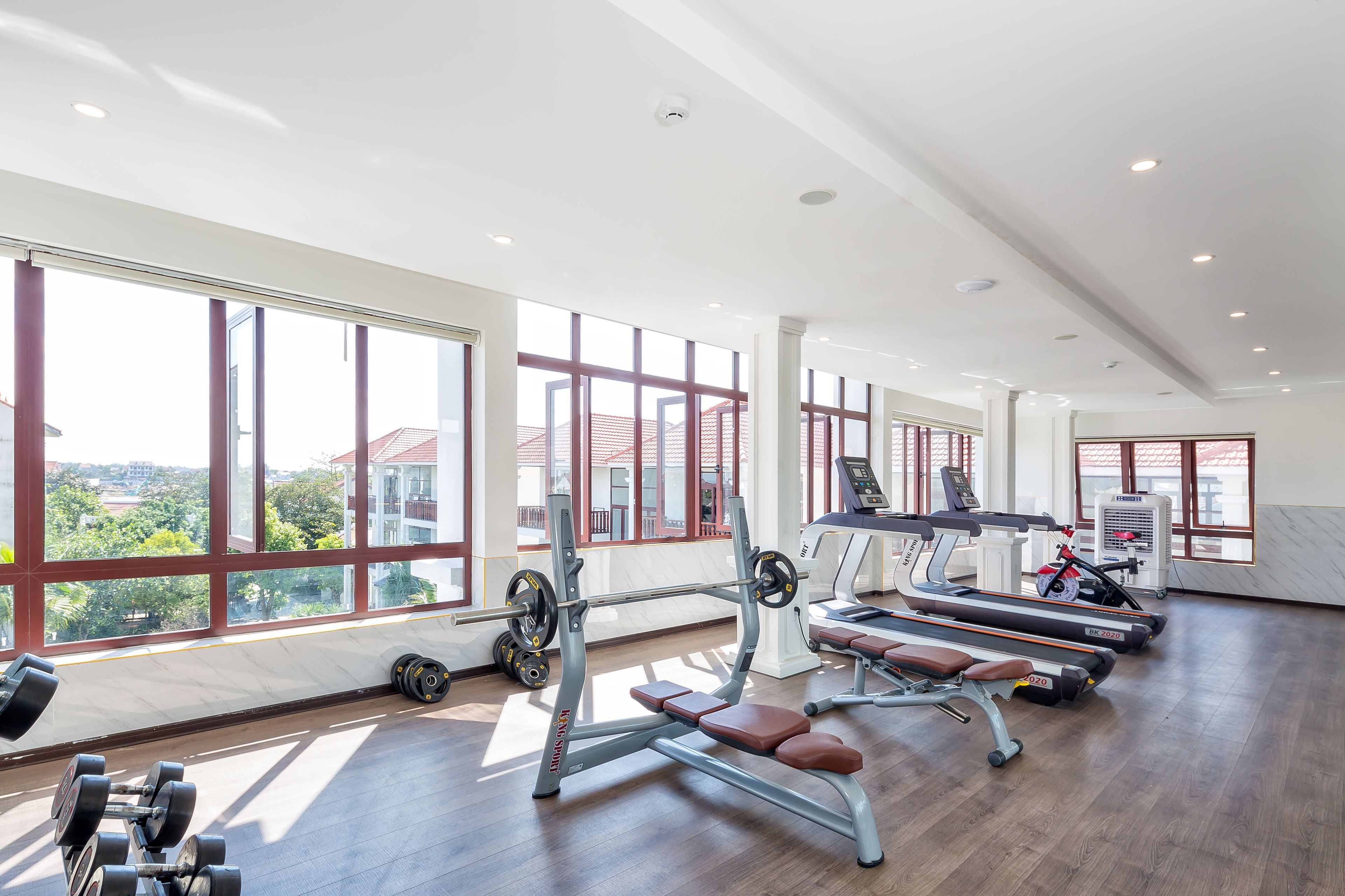 A gym with large windows, treadmills, and weight machines.