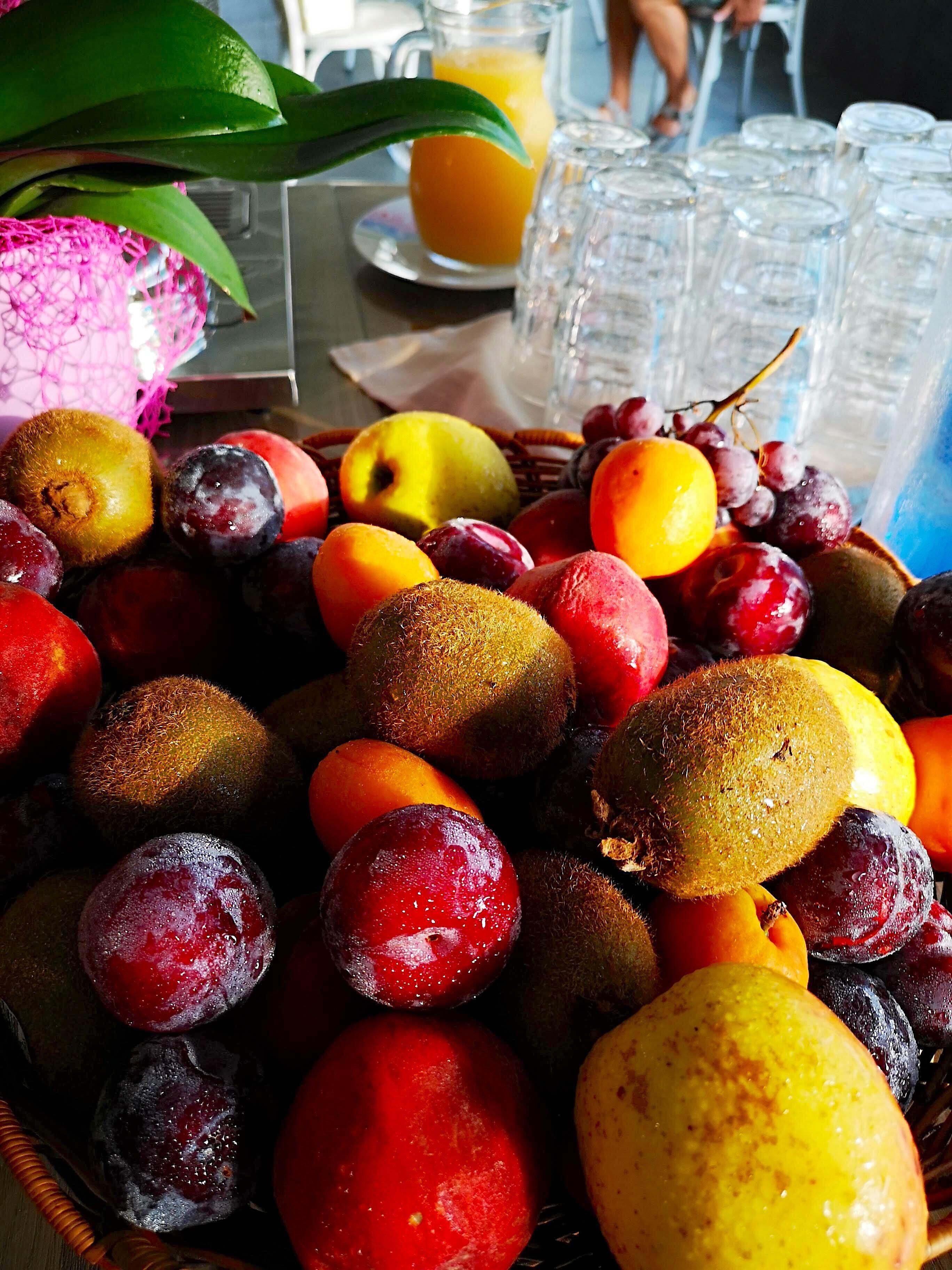 Een tafel met verschillende soorten fruit en een karaf sinaasappelsap.