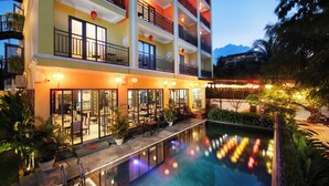 A multi-story hotel with outdoor seating and a swimming pool.