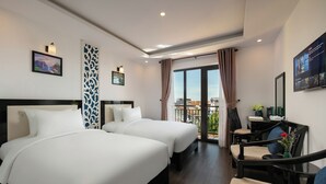 A hotel room with two beds, a desk with a chair, a TV, and a balcony with a view.