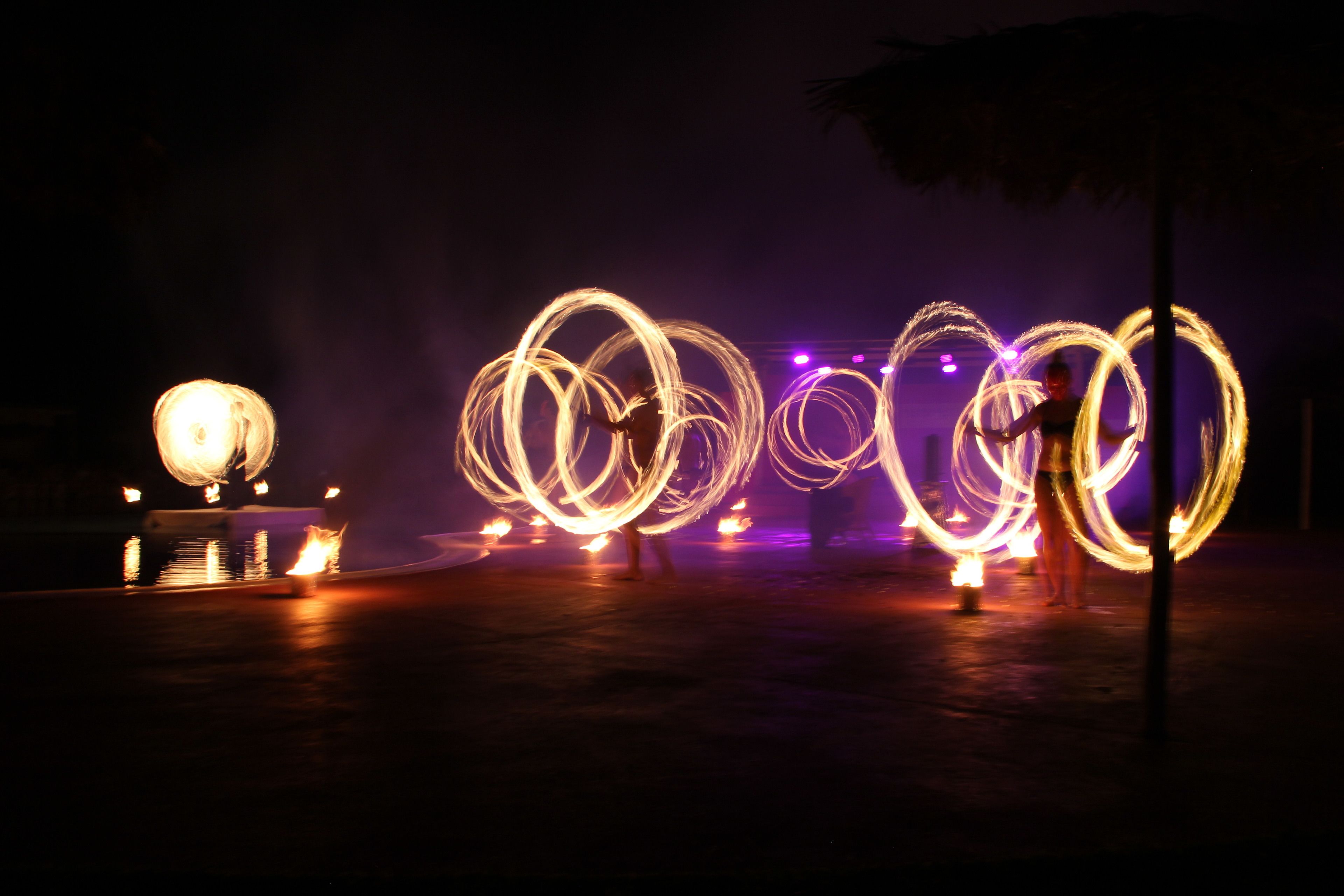 A nighttime scene with light trails from fire spinning performances.