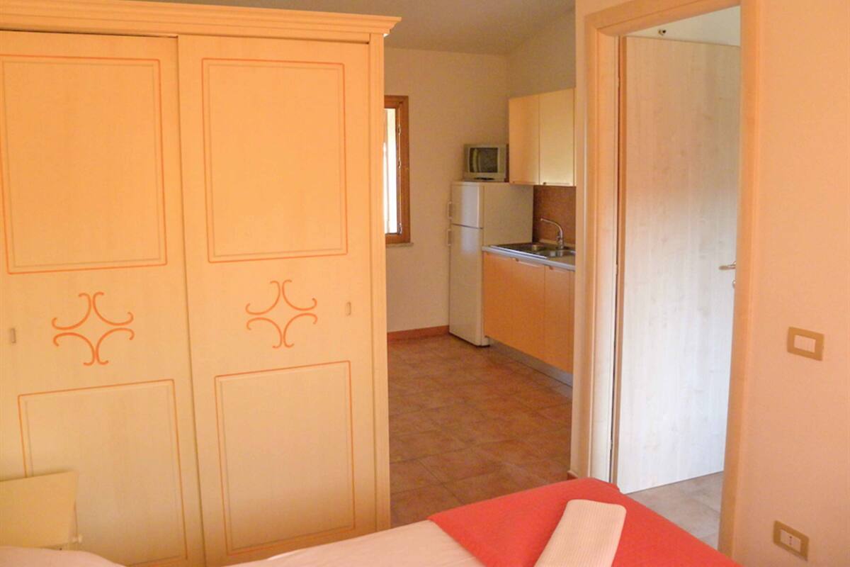 A compact room with a bed, a wardrobe, a kitchenette, and a bathroom.