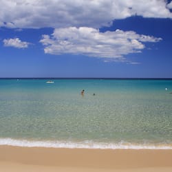 Na praia, areia branca, espreguiçadeiras, guarda-sóis