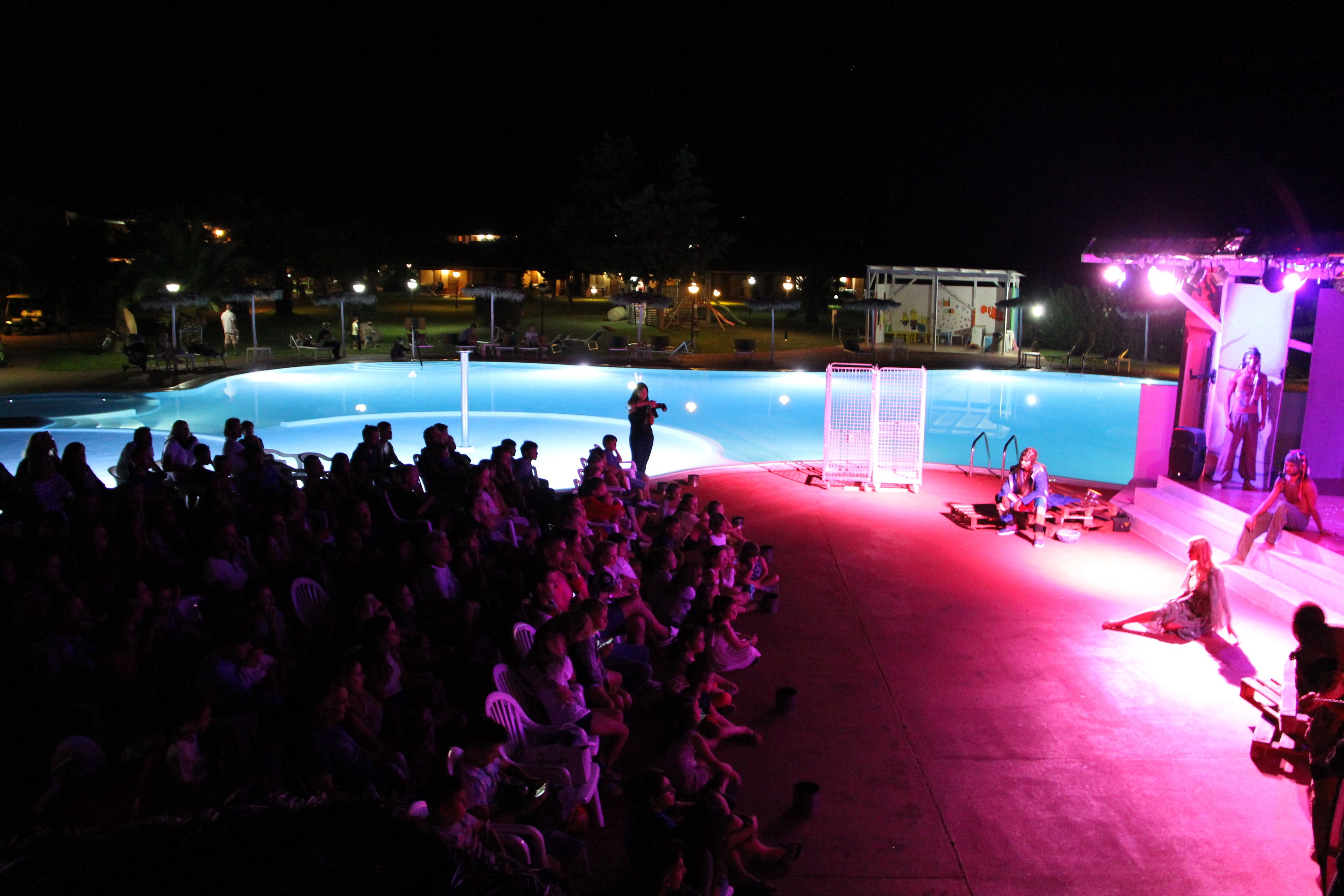A swimming pool with a stage and audience seating area.