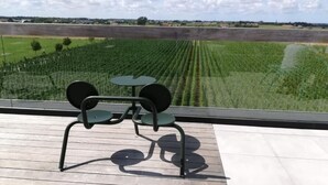 Un balcón con mesa y sillas que da a un campo.