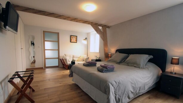 Un dormitorio con cama, mesitas de noche, televisión y techo de madera.
