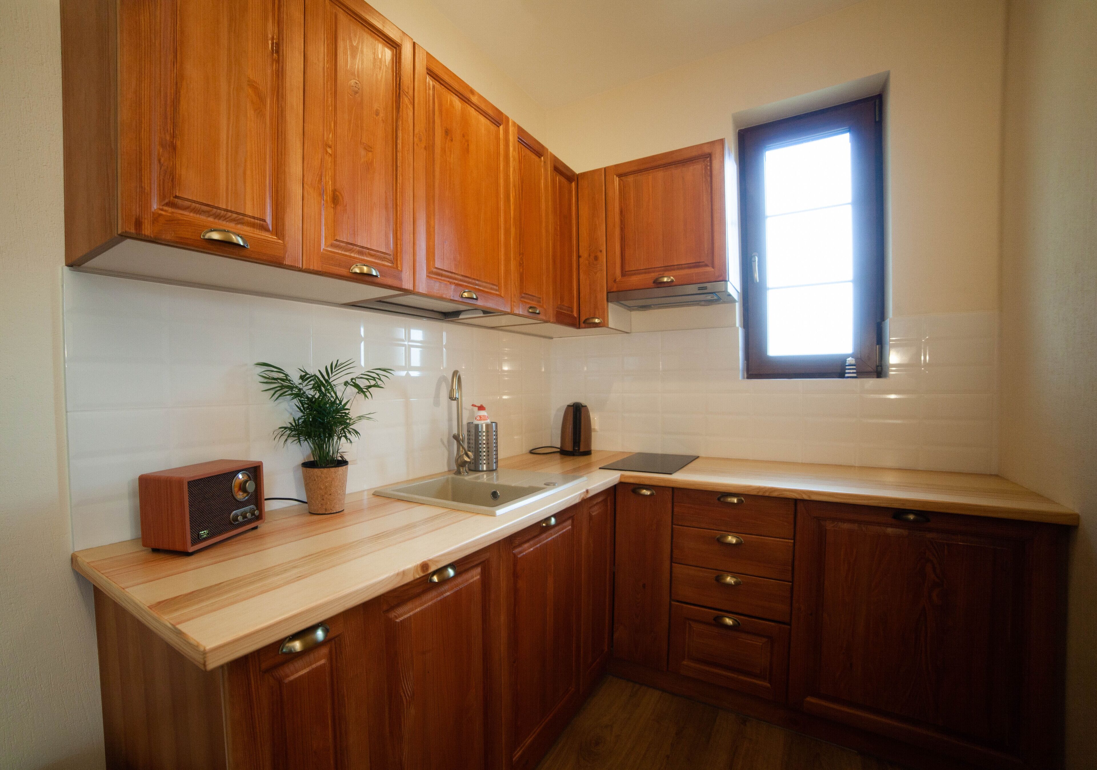 Una cocina con armarios de madera, un lavamanos, una ventana y un equipo de música.