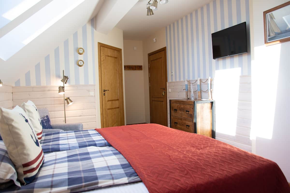 A bedroom with a bed, wooden wardrobe, and a TV on the wall.