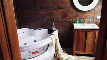 Un baño con una bañera blanca, un tocador de madera y un espejo redondo.