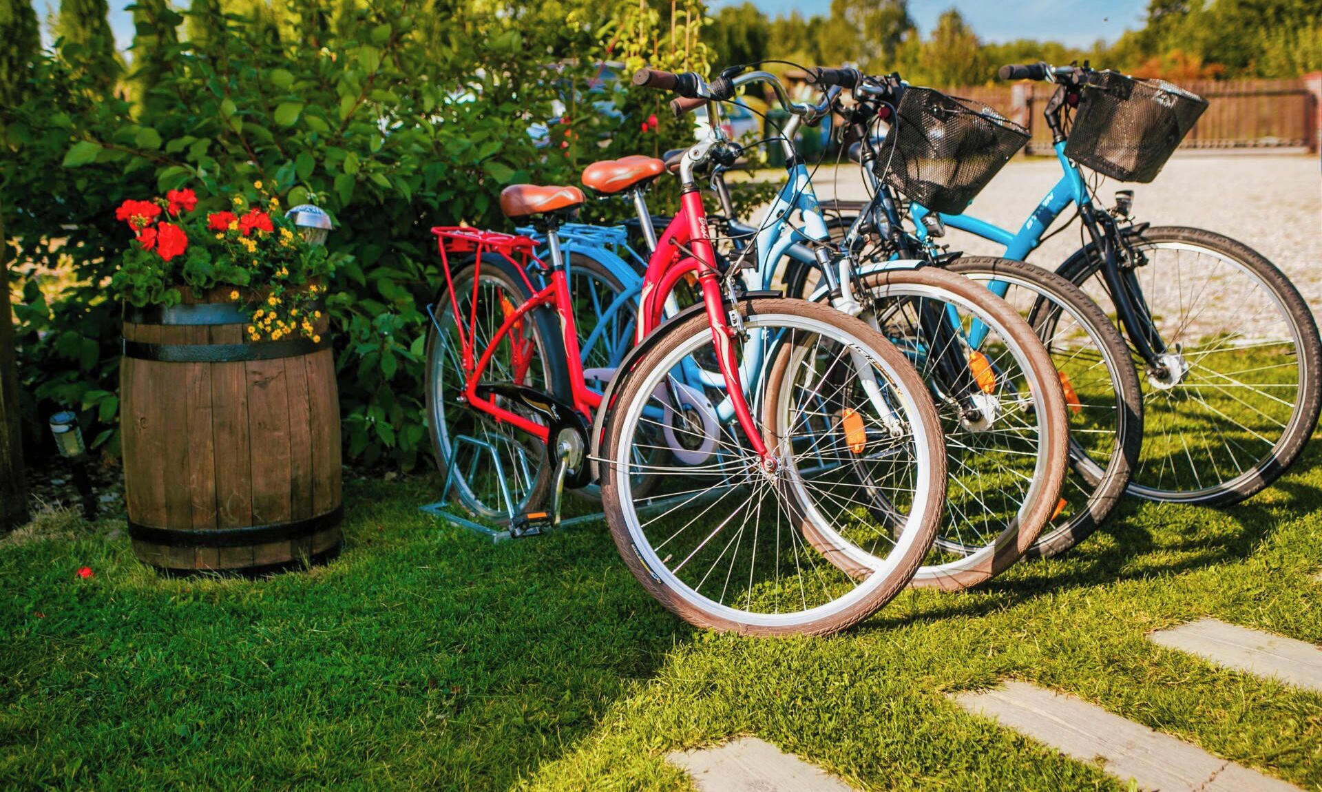 Bicicletas estacionadas en un césped con un barril de madera y flores al fondo.