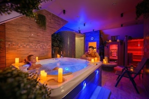 Et spaområde med jacuzzi, stearinlys og en liggestol.
