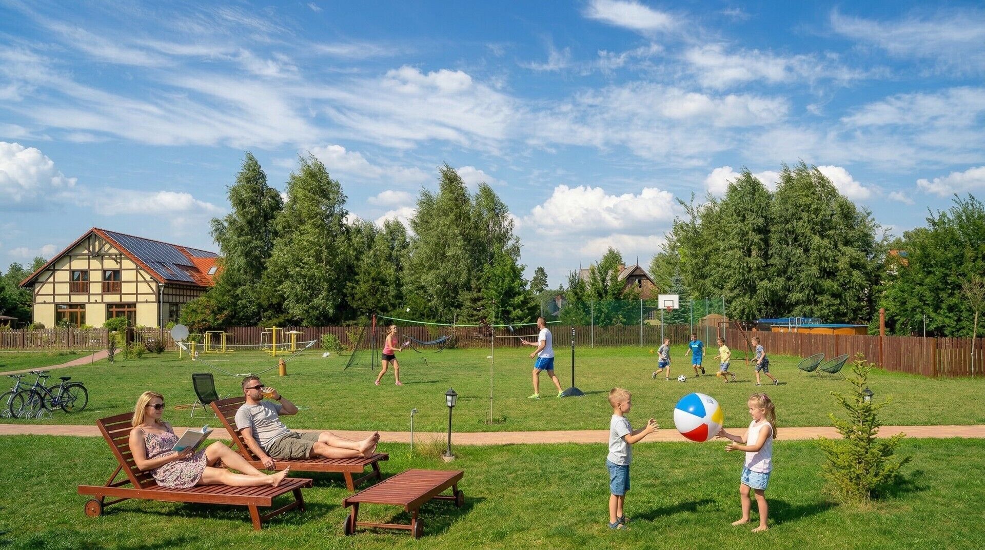 Une cour arrière avec une maison, un filet de volley-ball et des gens qui jouent.